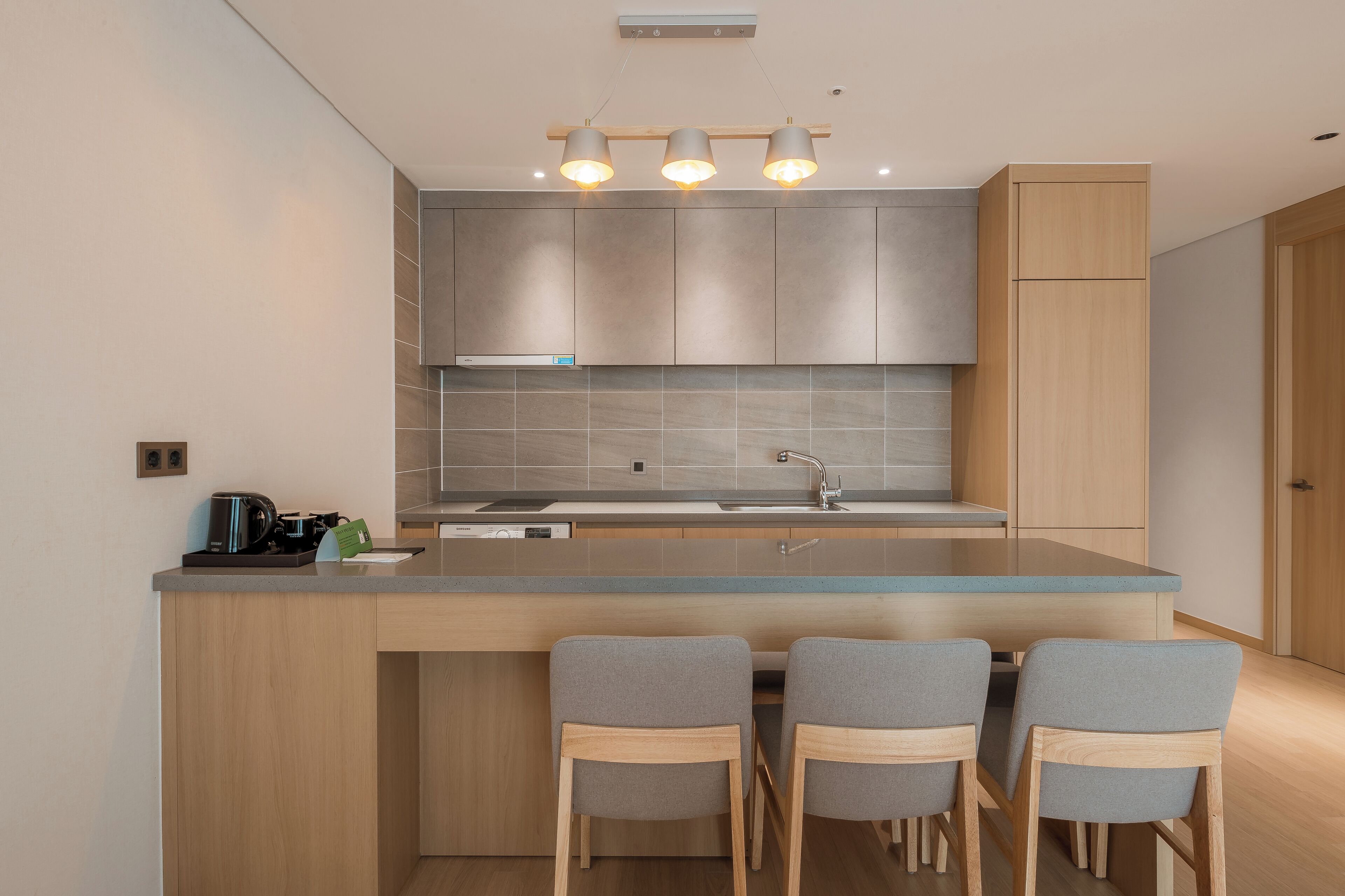 Een moderne keuken met een centraal eiland, inbouwkastjes en een roestvrijstalen spoelbak.