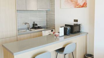 A modern kitchen with a bar area, a dishwasher, a microwave, and a coffee maker.