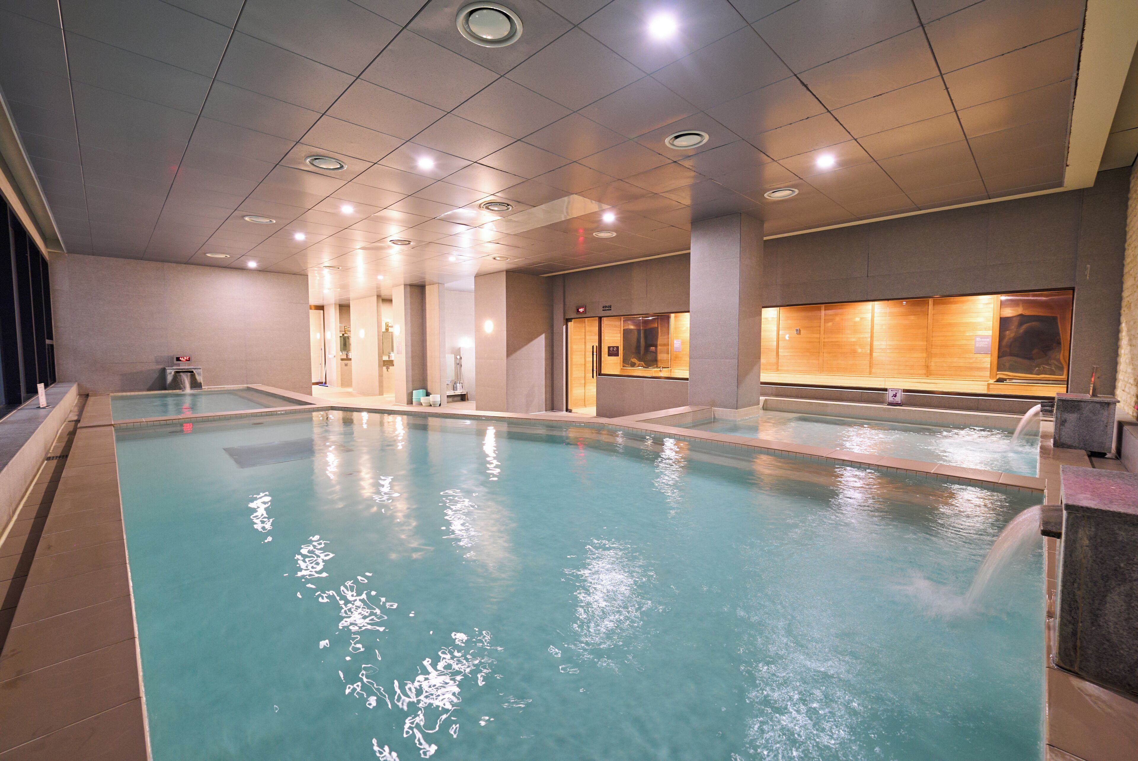 An indoor swimming pool with a tiled floor, a changing room, and a reception area.