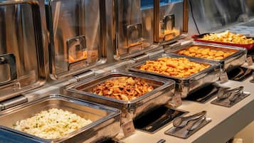 A buffet with various food options in metal containers, utensils, and a sign indicating a price of $8.99.