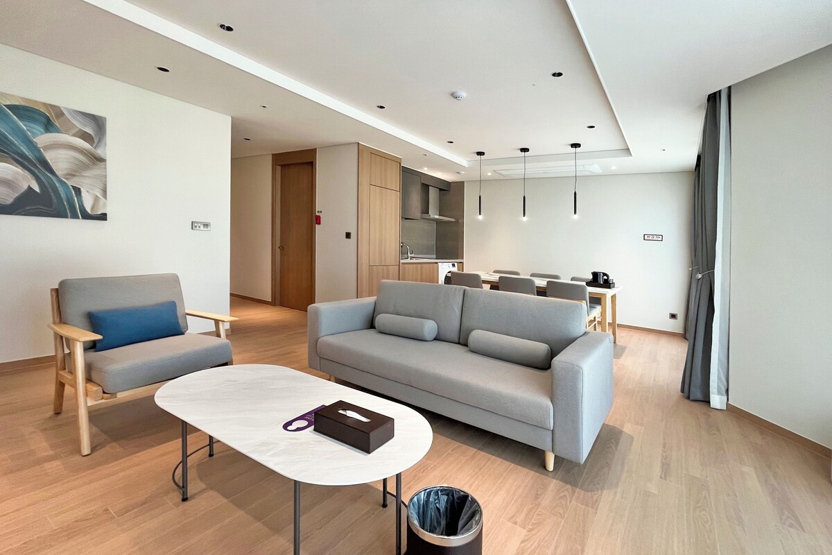 Una sala moderna con un sofá gris, una mesita redonda y un cubo de basura.