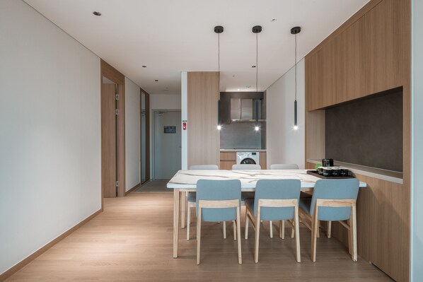 A modern kitchen with a dining area, wooden cabinets, and a built-in oven.