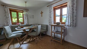 Una habitación con una mesa de madera, un sofá, un estante pequeño de madera y una cruz en la pared.