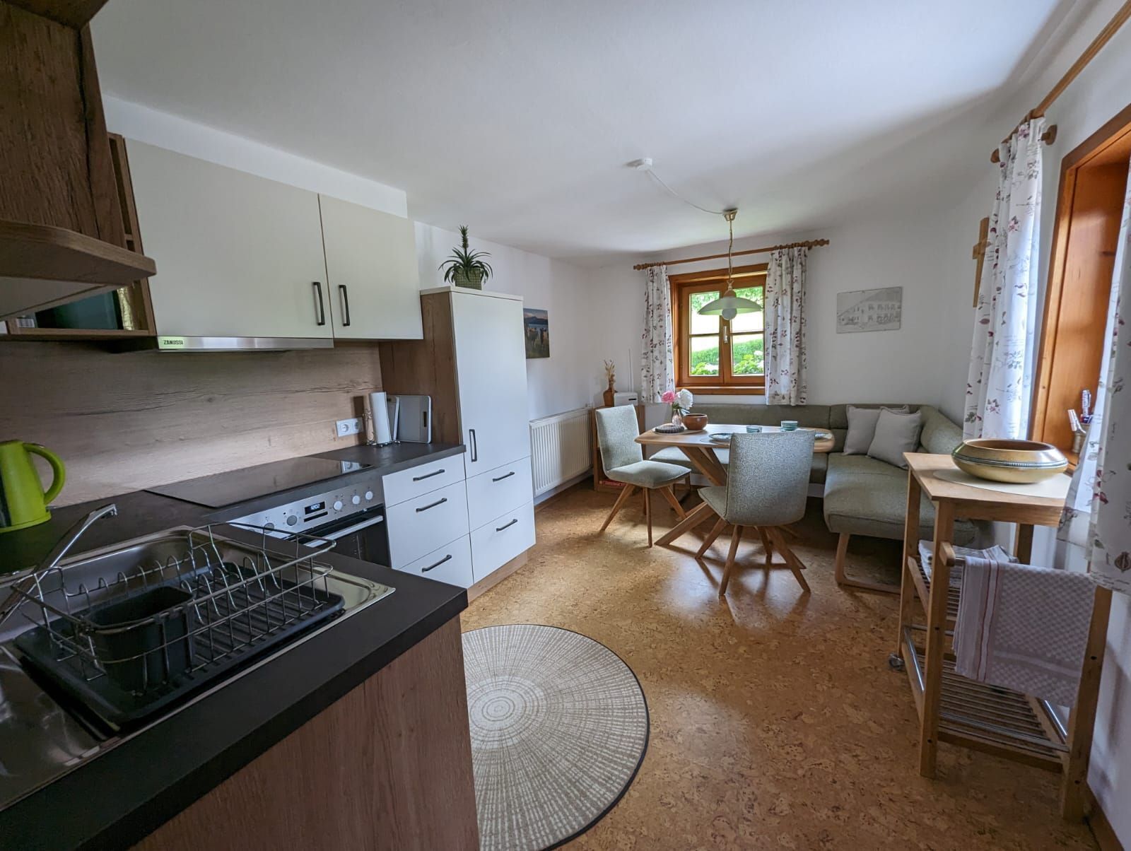 Eine kompakte Küche mit modernen Geräten, ein Essbereich mit Tisch und Stühlen und eine gemütliche Sitzecke mit einer Couch.