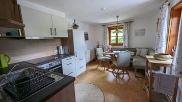 Eine kompakte Küche mit modernen Geräten, ein Essbereich mit Tisch und Stühlen und eine gemütliche Sitzecke mit einer Couch.