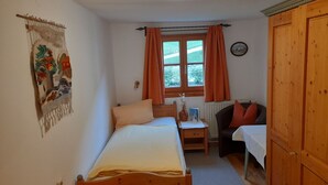 Un dormitorio con dos camas, un escritorio, una silla, un armario y una ventana con cortinas.