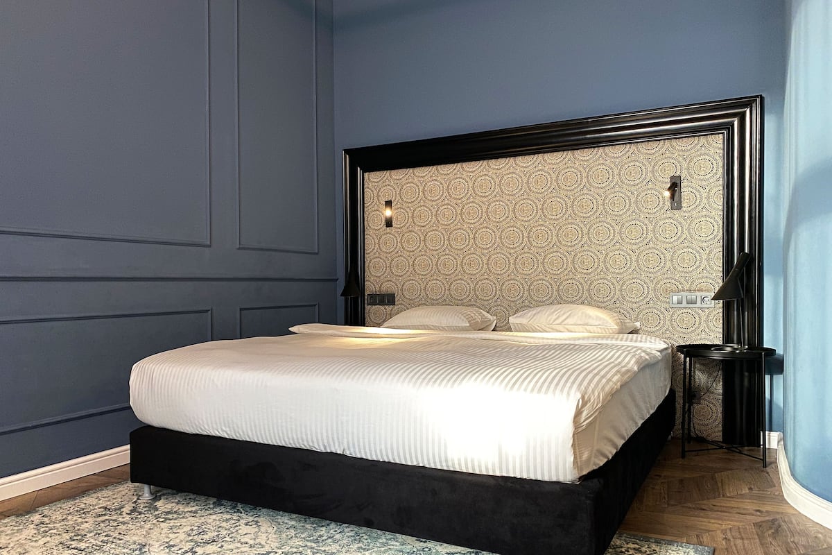 A bedroom with a bed, a headboard, a nightstand, and a lamp.