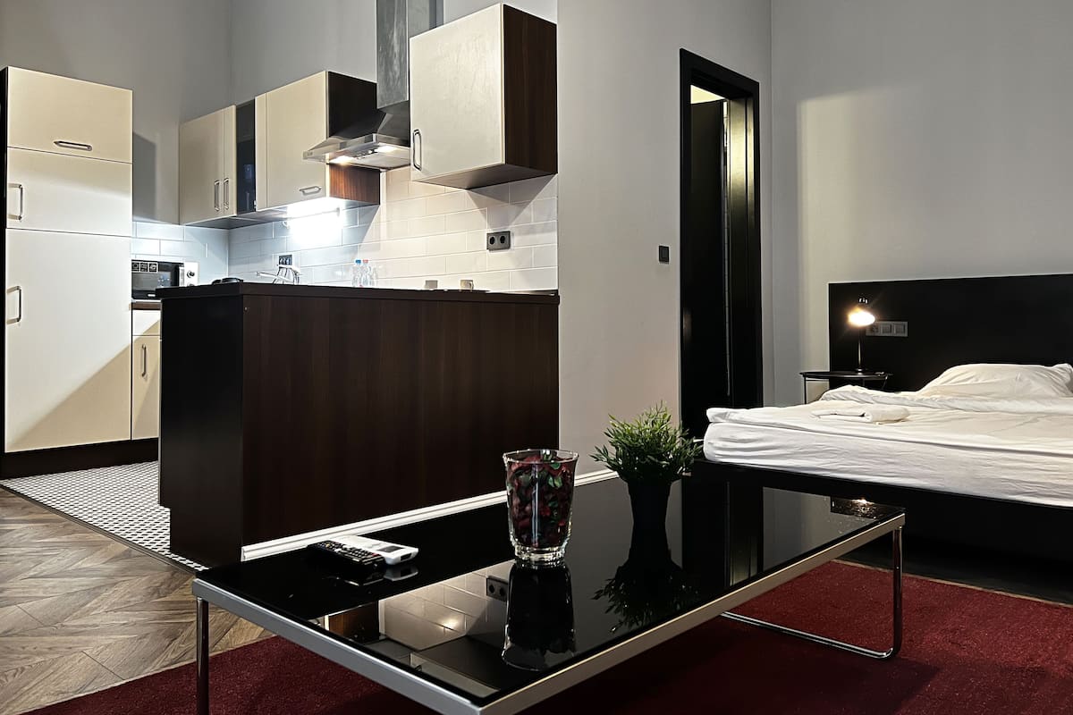A modern kitchen with a dining table and a bed in the adjacent room.