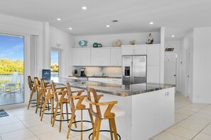 A modern kitchen with a large island, bar stools, and a view of the outdoors.