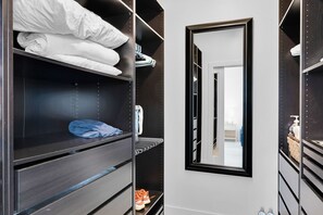 Ein begehbarer Kleiderschrank mit Regalen, einem Spiegel und einer Tür zu einem anderen Raum.