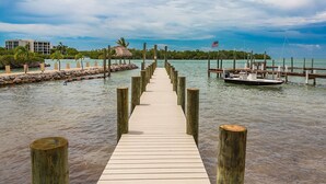 A wooden pier leading to a dock with a boat, surrounded by calm water and a clear sky. - 5 Seas Retreat 4 bed 2 bath dock, pool, Sandy Beach Dockage For up to a 25 ft boat (Marathon)