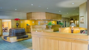 A hotel lobby with a reception desk, seating area, and a small dining table. - Midway Inn (Middelburg)
