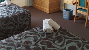 A hotel room with two beds, a wooden wardrobe, a desk with a chair, a mirror, and a bathroom with a shower. - Midway Inn (Middelburg)