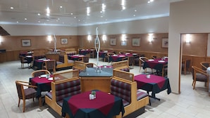 A restaurant with booths and tables, wooden walls, and ceiling lights. - Midway Inn (Middelburg)