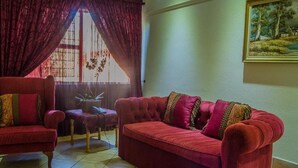 A living room with a red sofa, a red armchair, and a patterned rug. - Midway Inn (Middelburg)