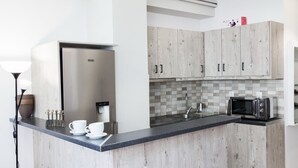 A modern kitchen with wooden cabinets, a built-in microwave, and a coffee machine.