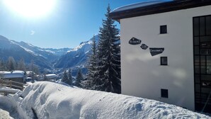 Eine verschneite Berglandschaft mit einem Gebäude, auf dem „Residence Les Chavonnes“ steht.
