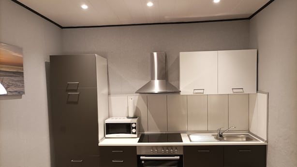 A compact kitchen with a microwave, oven, and sink. - Vacation apartment (Moormerland)