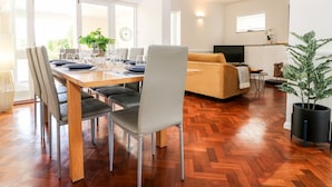 A modern living space with a dining area, sofa, TV, and potted plants. - 5 Sea Way (Bognor Regis)