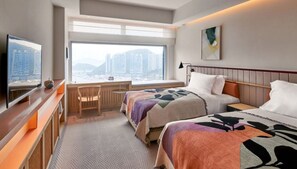 A hotel room with a bed, a desk, a chair, a TV, and a large window with a city view. - The Arca (Hong Kong Island)
