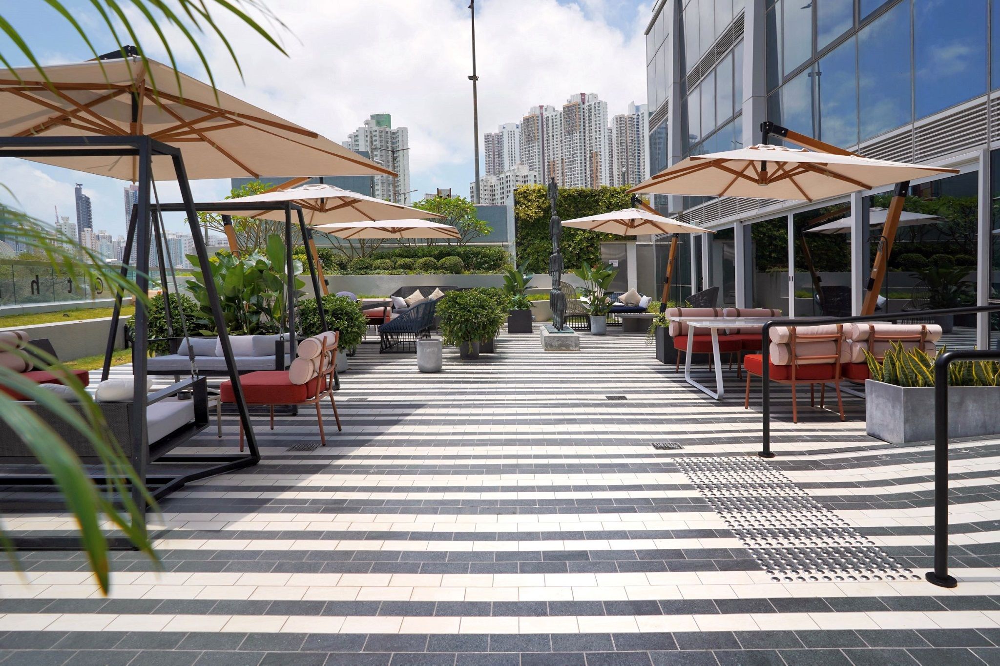 A rooftop terrace with outdoor seating, umbrellas, and a city view.