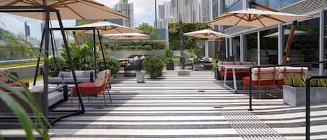 Terraza en la azotea con asientos exteriores, sombrillas y vistas a la ciudad.