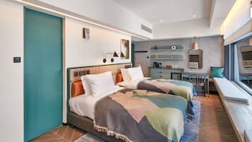 Ett modernt hotellrum med två sängar, ett litet skrivbord, en sittgrupp vid fönstret och ett litet pentry.