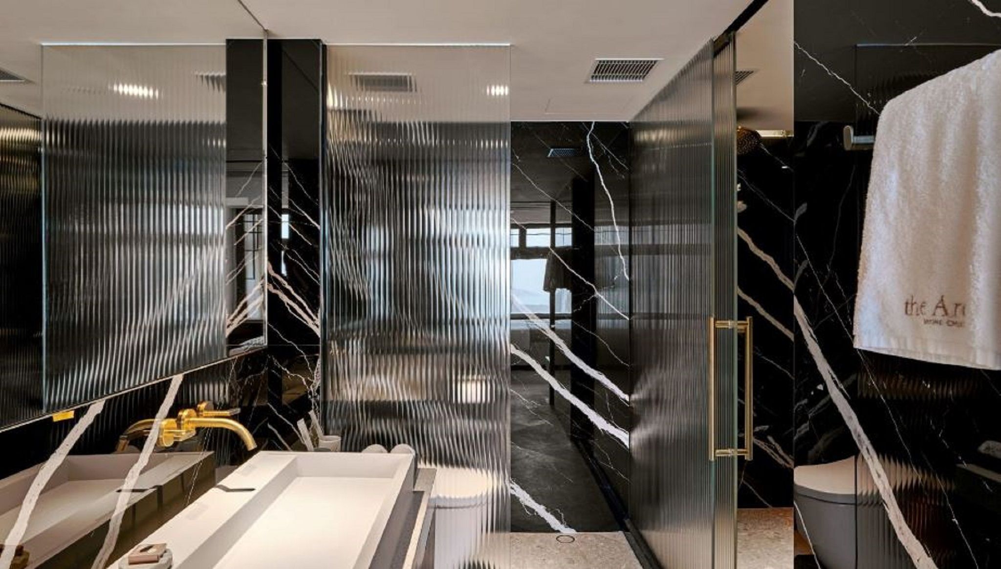 A modern bathroom with a large mirror, a sink, and a towel rack.