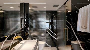 A modern bathroom with a large mirror, a sink, and a towel rack.