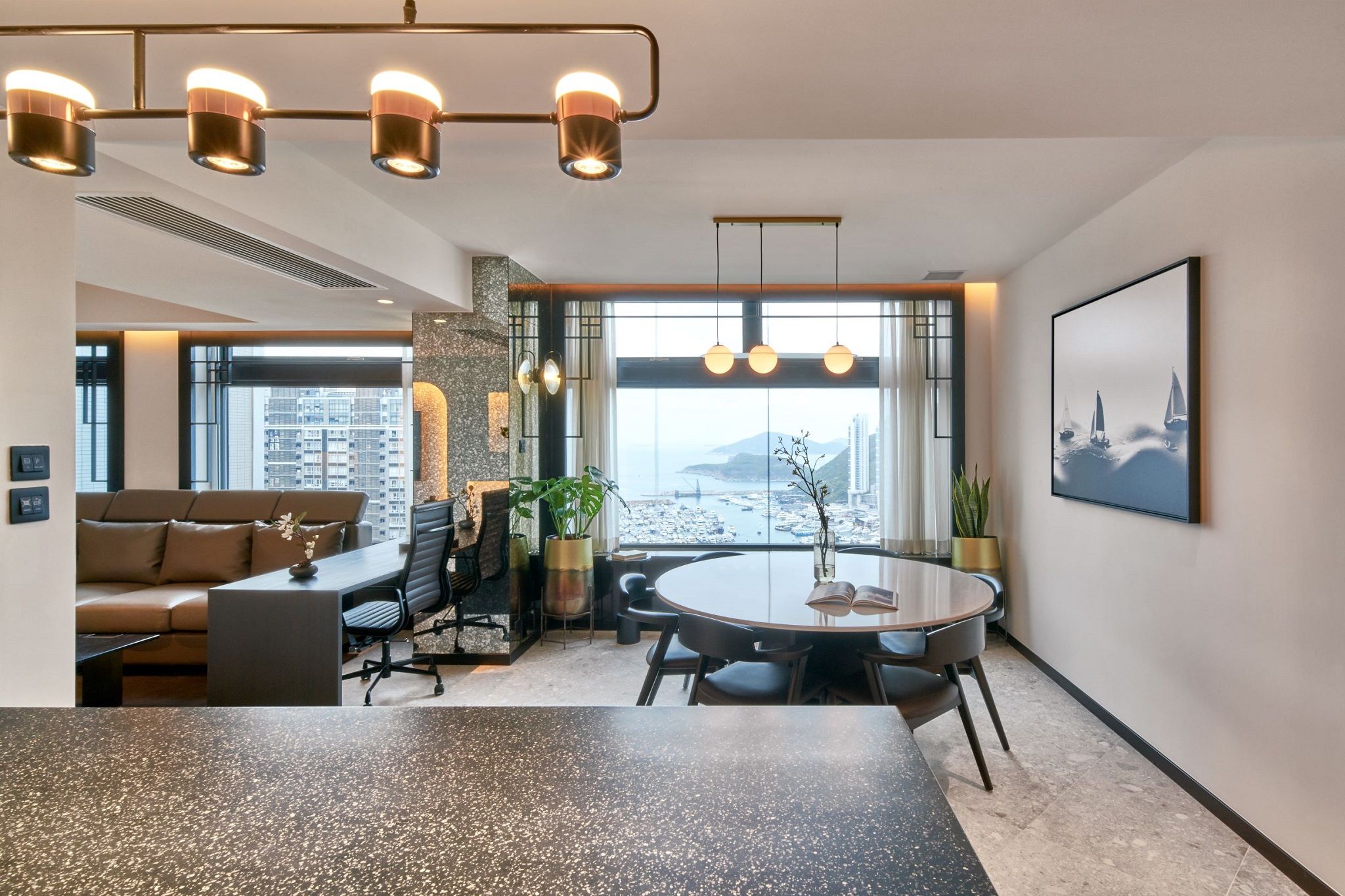 A modern office space with a round table, leather sofa, and potted plants.