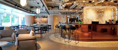 Un interior moderno con una zona de bar, asientos y una cocina a la vista.
