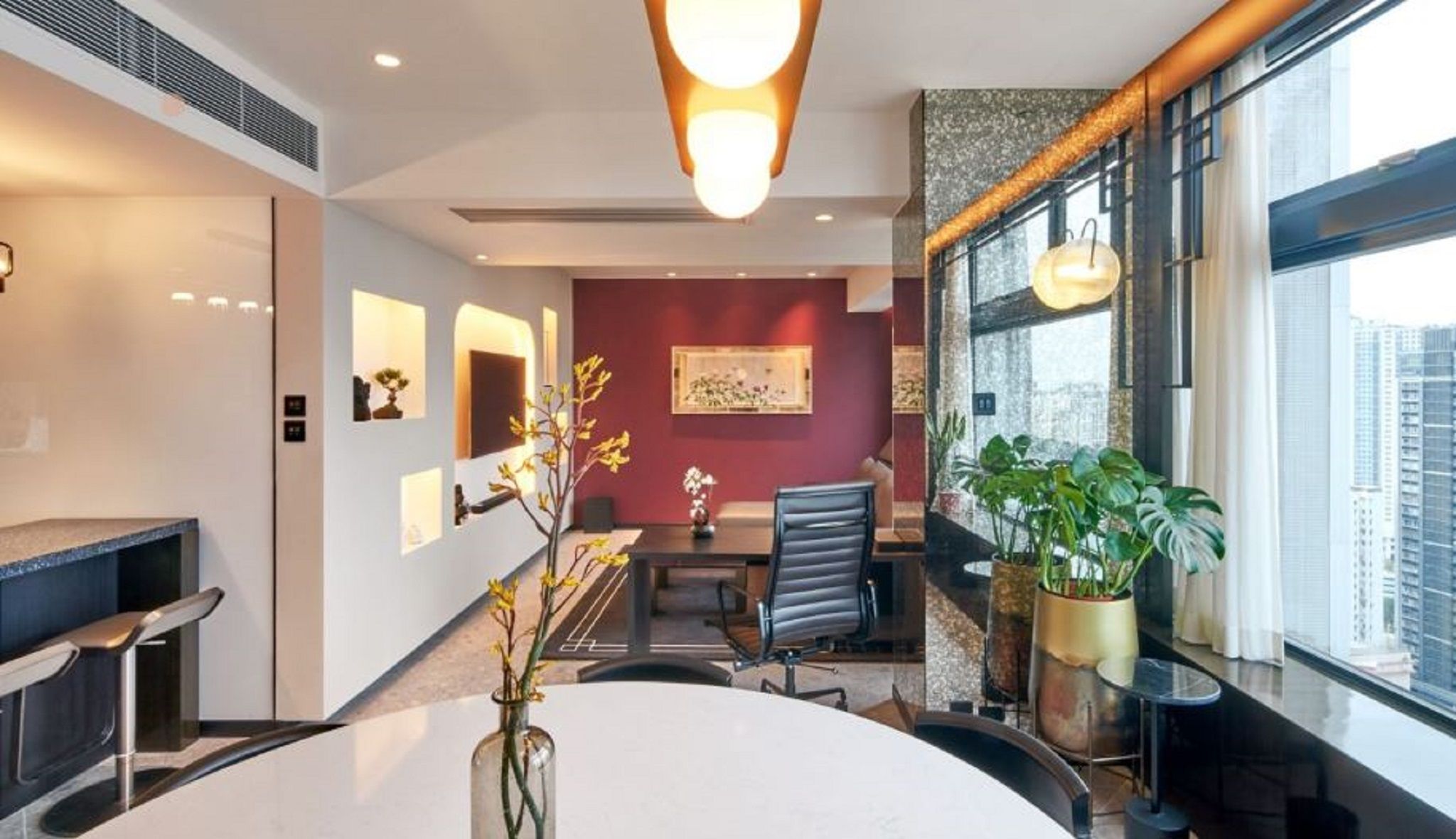 A modern office space with a round table, chairs, a staircase, and large windows.