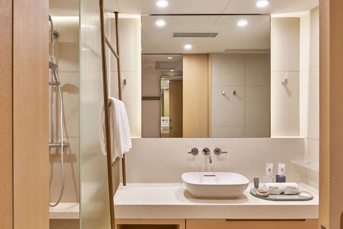 A modern bathroom with a large mirror, a sink, and a shower.