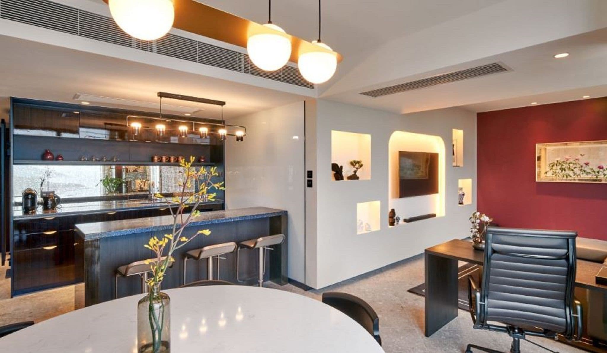 Una cocina moderna con barra, una mesa de comedor y sillas, y una pared de acento roja.
