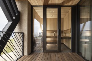 Un interior moderno con suelo de madera, un ventanal de vidrio que da a un balcón y vistas al exterior.