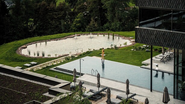 A modern building with a rooftop pool, surrounded by lush greenery and mountains in the background. - Santre dolomythic home (Bressanone)