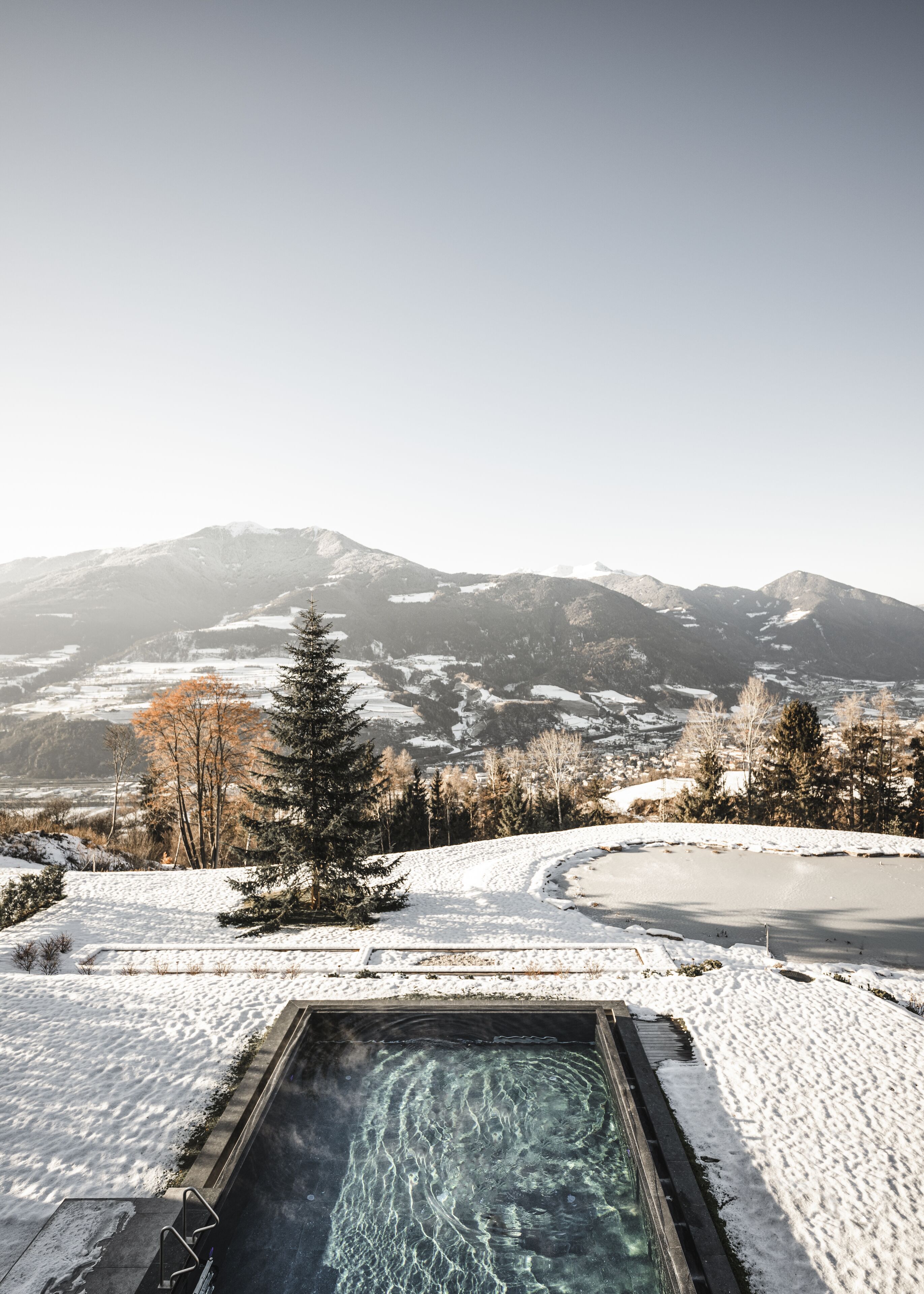 Un espacio exterior cubierto de nieve con una piscina y vistas a las montañas.