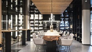 A modern dining area with a long table, comfortable chairs, and wine racks in the background. - Santre dolomythic home (Bressanone)