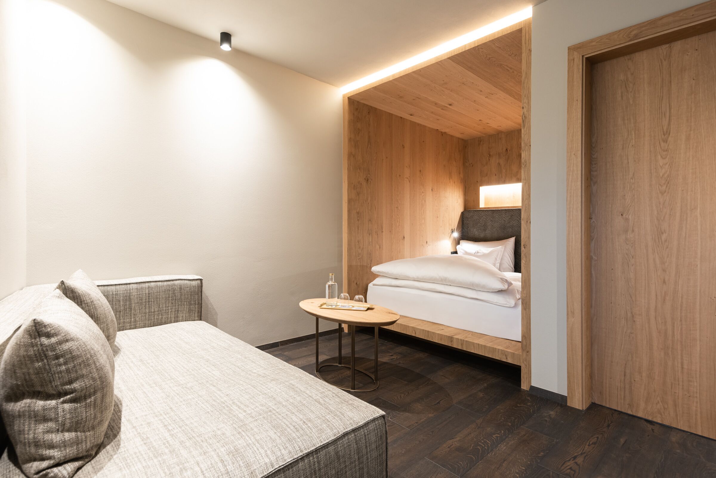 A modern hotel room with a bed, a small table, and a sofa.
