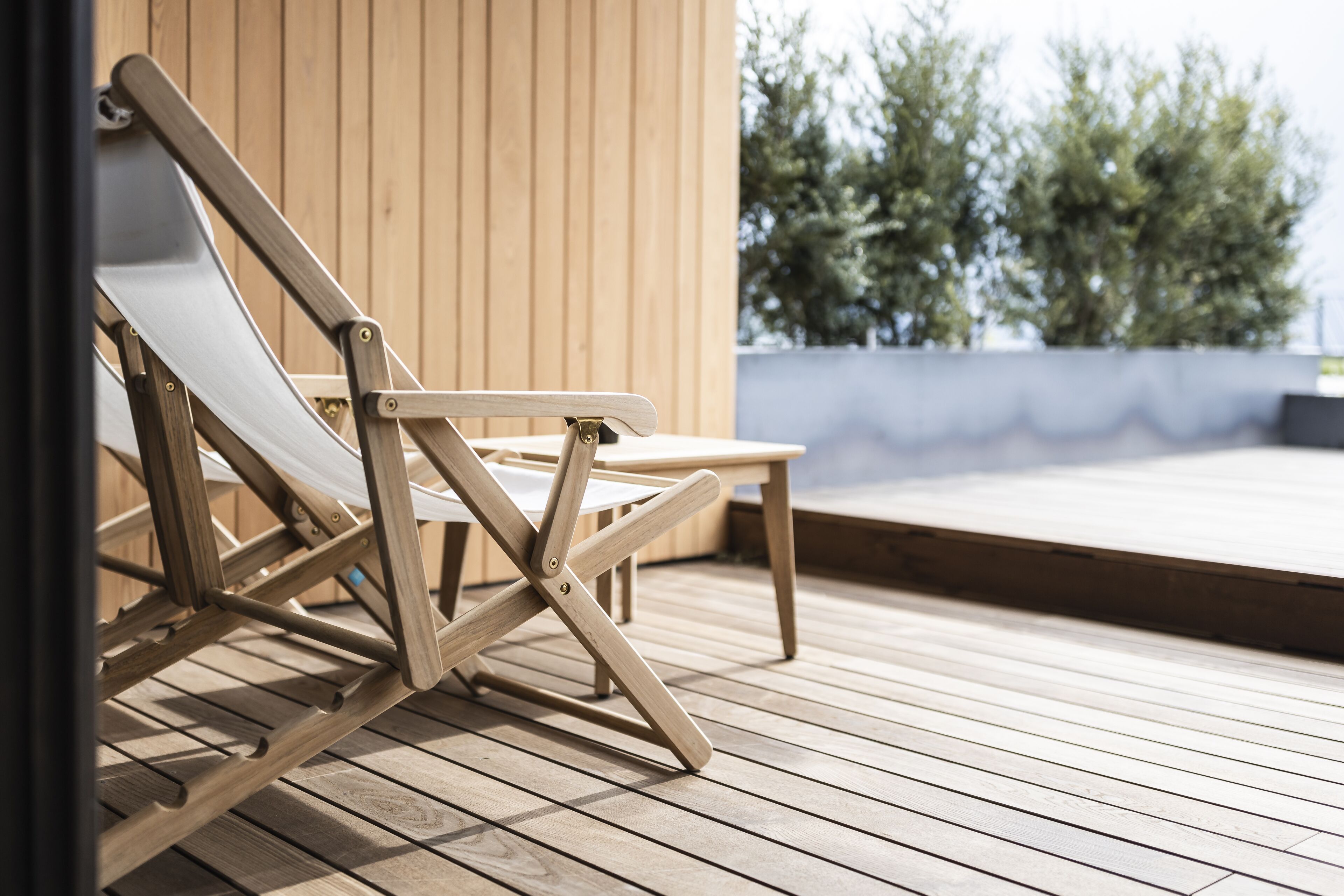 A wooden deck with a folding chair and a small table.