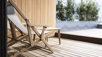 A wooden deck with a folding chair and a small table.