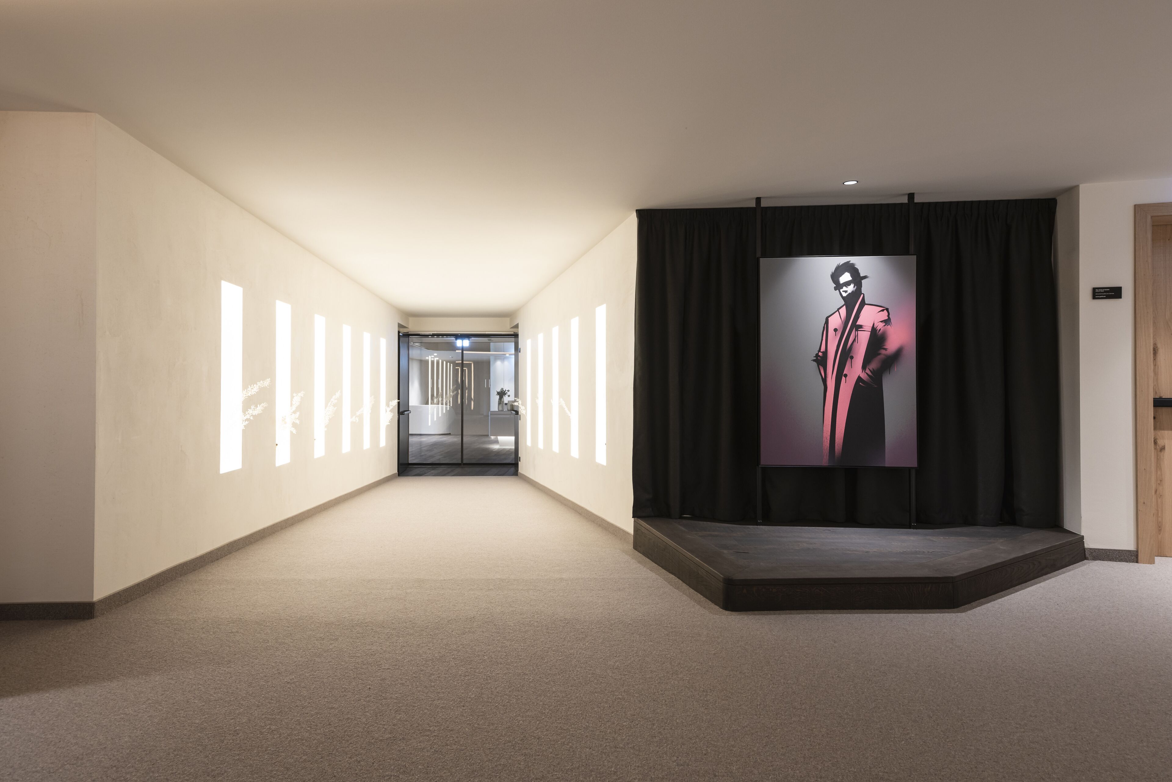 Un pasillo de diseño moderno, con una gran pantalla digital mostrando una figura con traje.