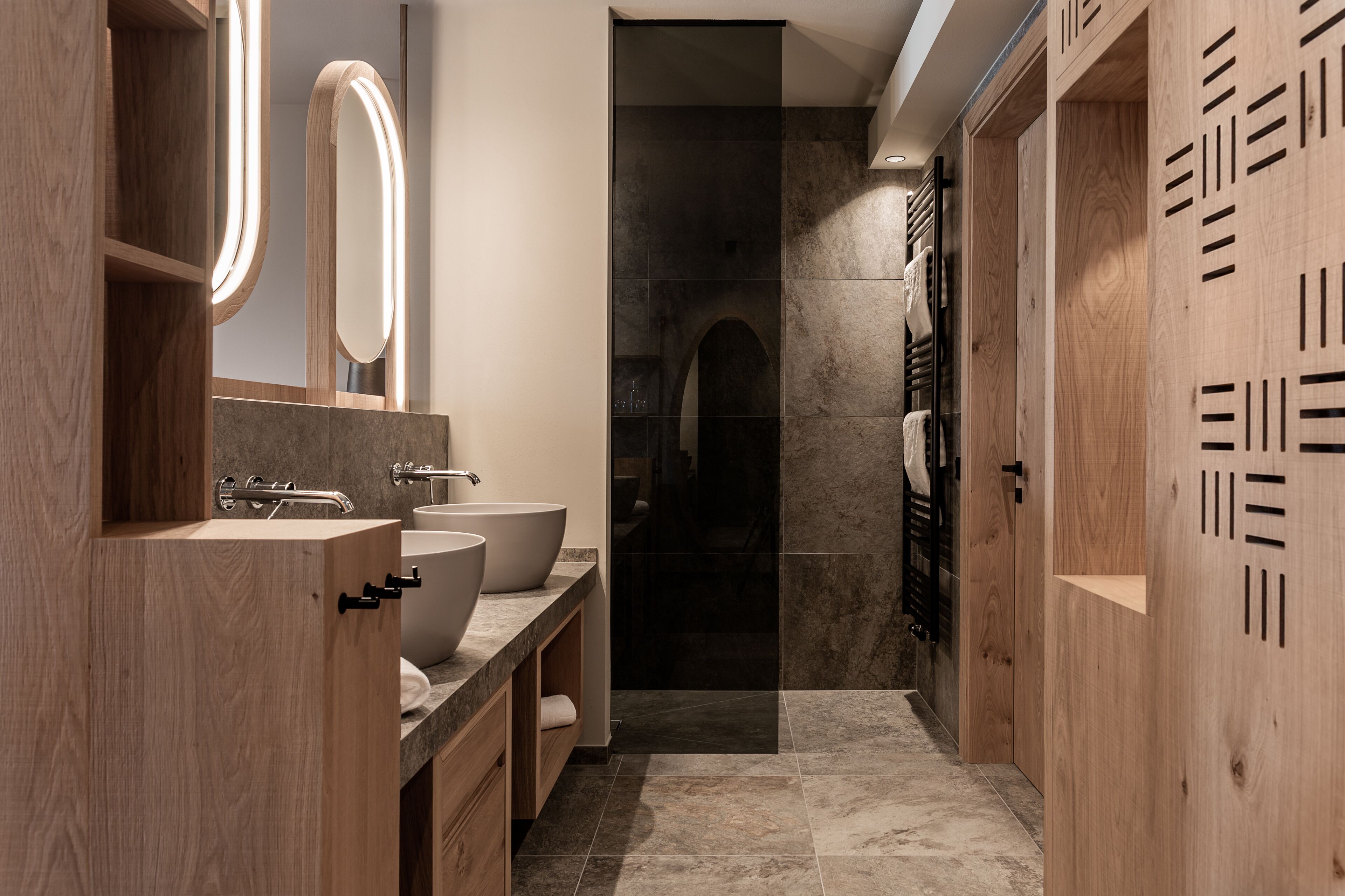 A modern bathroom with wooden cabinetry, a large mirror, and a walk-in shower.