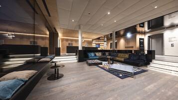 Een ruime lobby met een modern design, met een zithoek met banken en een salontafel, een receptiebalie en een trap naar een lift.