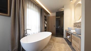 A modern bathroom with a freestanding bathtub, a large mirror, and a vanity with two sinks.