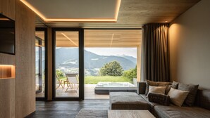 A modern living room with a large window, a sofa, and a wooden floor. - Santre dolomythic home (Bressanone)