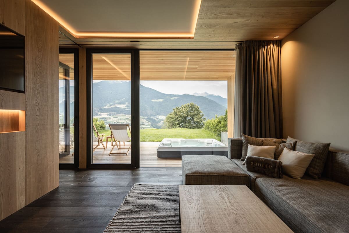 A modern living room with a large window, a sofa, and a wooden floor.