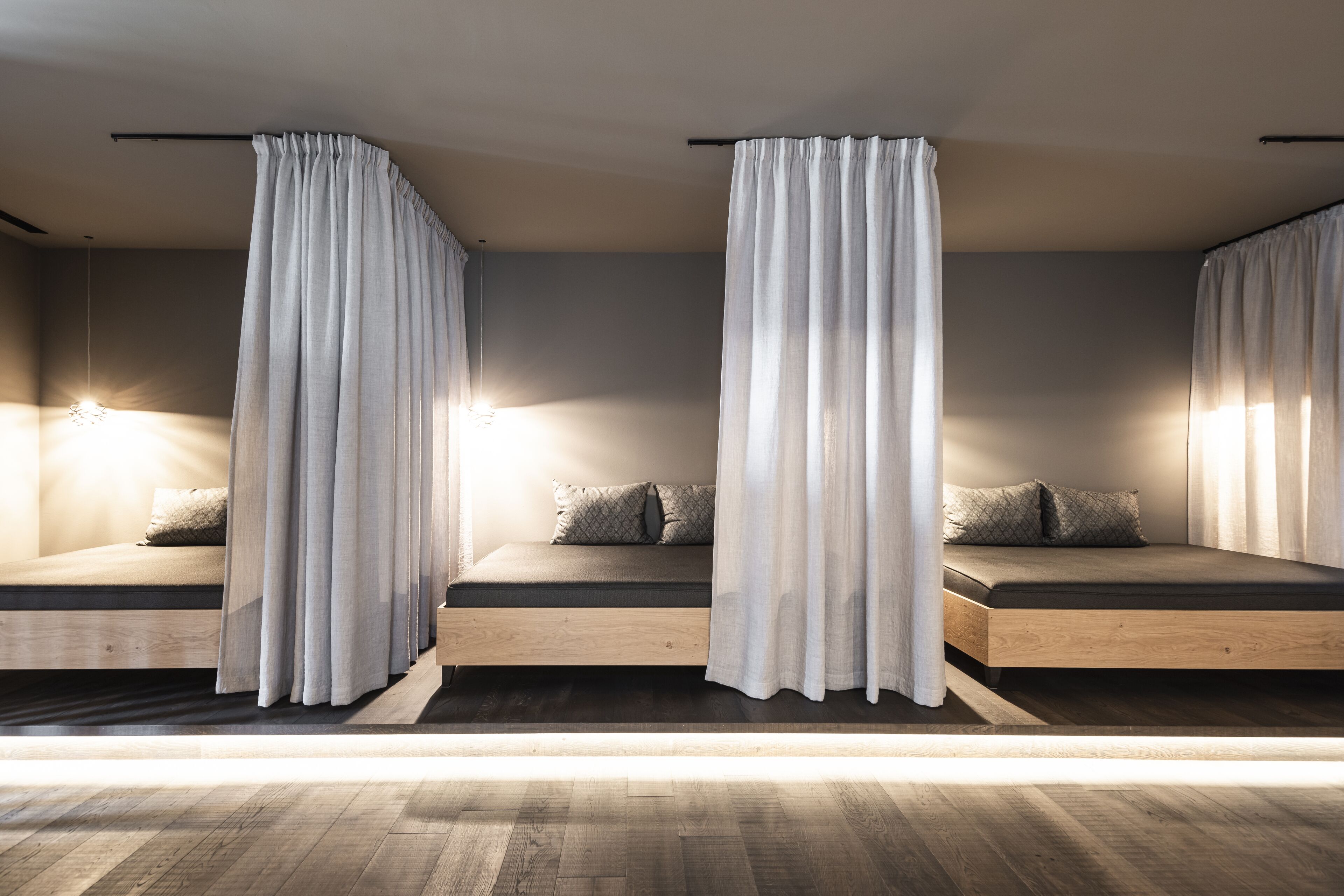 A modern bedroom with two beds, each with a wooden frame and a headboard, separated by a curtain.