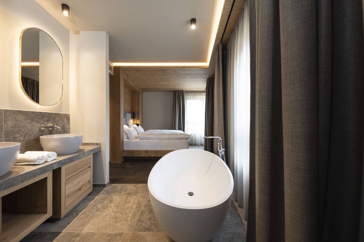 A modern bathroom with a freestanding bathtub, a large mirror, and a vanity with two sinks.