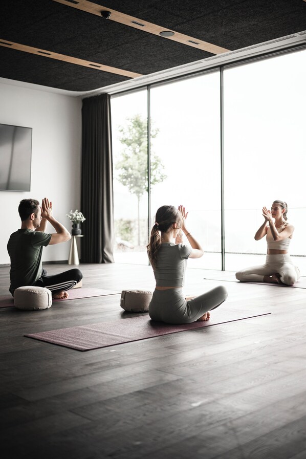A yoga class in a modern room with large windows, wooden floors, and minimalistic decor.